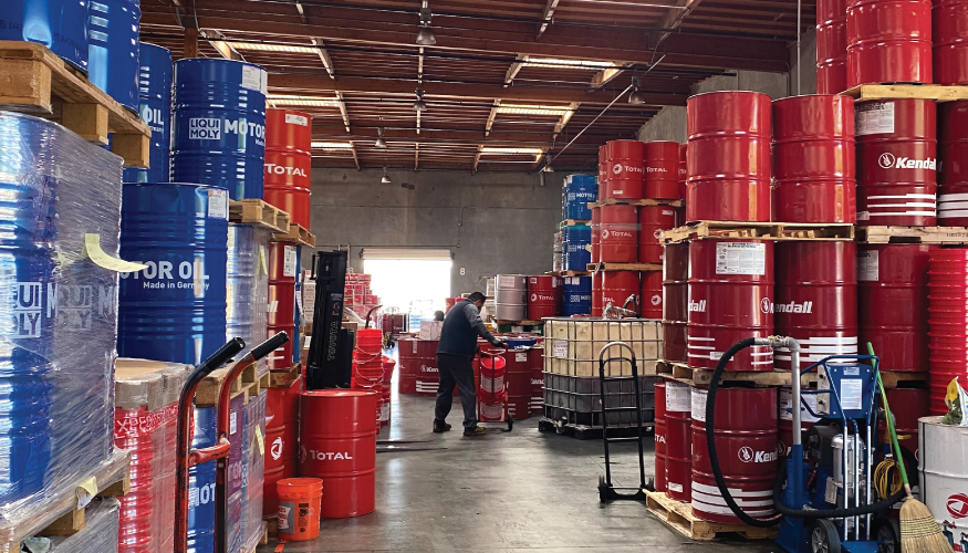 A picture of a person in the middle of a warehouse that stages cases, drums, and totes of lubricants, motor oils, greases, and DEF.