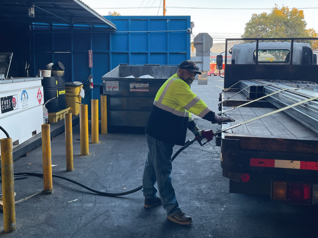 A picture of a worker fueling up a vehicle in a secured company yard using one of our bulk tanks.
