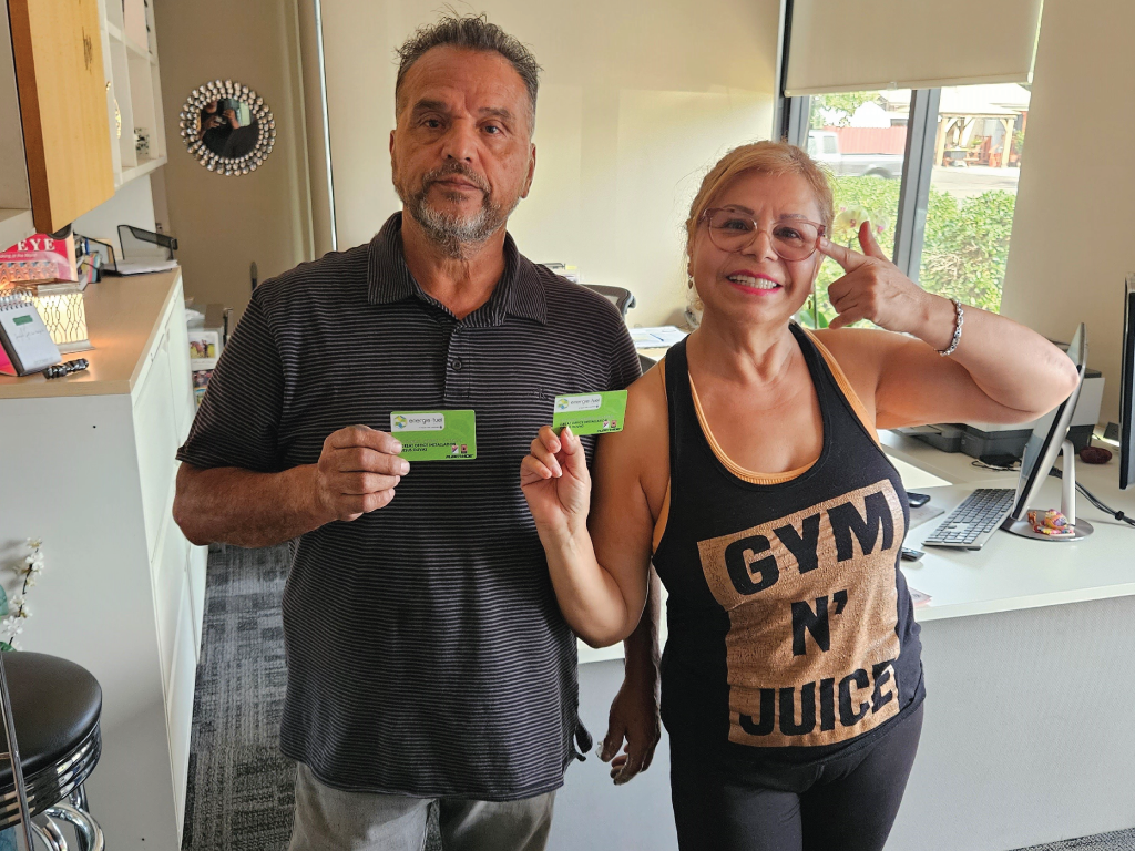 A picture of two people posing and holding energie·fuel cards while in their office.