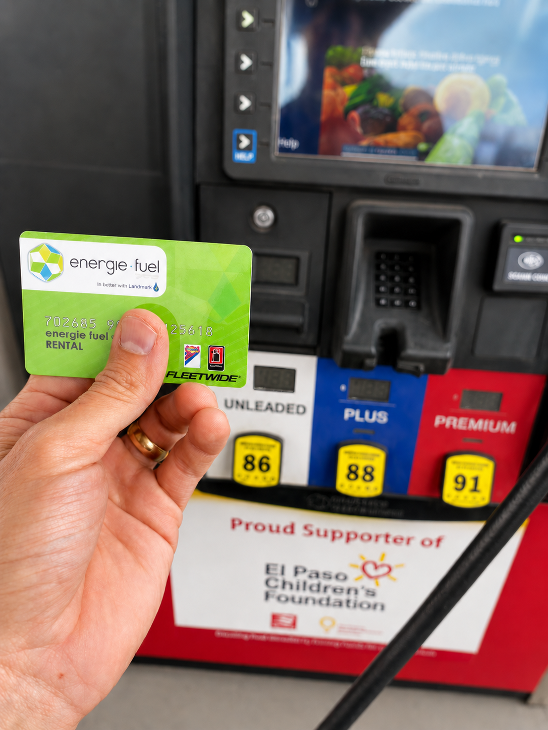 Person holding Energie Fuel card in front of the pump.