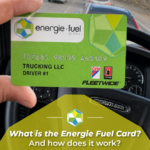 A hand holds an Energie Fuel Group Fleetwide fuel card inside a vehicle, with a truck dashboard and steering wheel visible in the background.